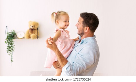 Sweet Moments Of Parenting. Portrait of young bearded man carrying his adorable daughter in cozy apartment