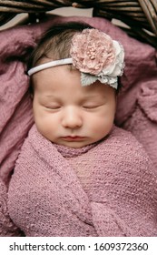 Sweet Newborn Baby Girl Swaddled And Bundled Up In A Blanket Wrap Laying In A Wooden Basket Close Up