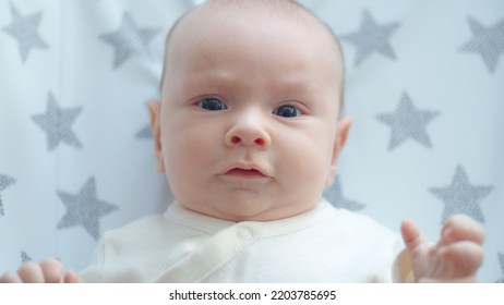 Sweet Newborn Boy Lies On The Sofa. Beautiful Infant Boy With Blue Eyes.  Cute Two-month-old Baby In White Clothes. High Angle View Of A Chubby Male Kid.  Closeup Portrait Of Calm Baby.