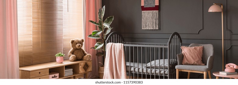 Sweet, Pastel Pink Accessories In A Classic, Dark Nursery Bedroom Interior With Wooden Furniture And A Gray Crib For A Child