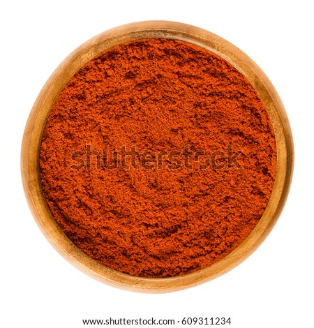 Sweet pepper red paprika powder in wooden bowl. Ground spice made from air-dried and smoked bell peppers, Capsicum annuum. Hungarian cuisine. Macro food photo close up from above on white background.