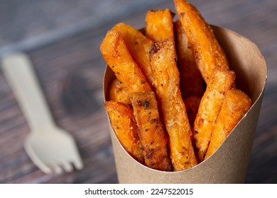 Sweet potato fries in a takeaway card container box with a wood fork. Disposable recycling sustainable plastic free takeaway packaging - Shutterstock ID 2247522015
