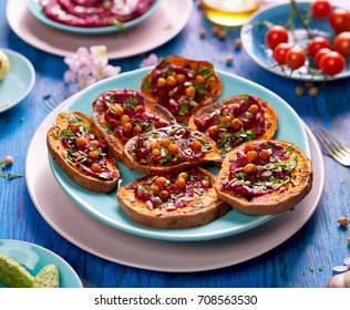 Sweet potato toast with addition of beet hummus, olive oil, grilled chickpeas, sunflower seeds, nigella and fresh parsley on a plate on a blue table, top view. Healthy and delicious vegan food. 