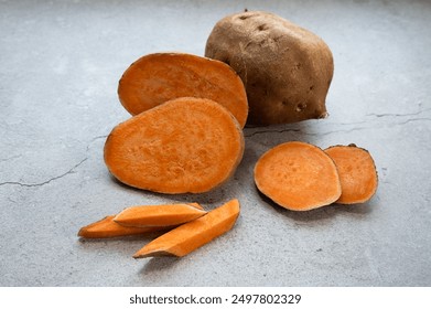 Sweet potato or yam roots, both whole and sliced, rest on a light surface.