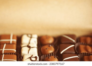 Sweet present concept. A set of hand-made chocolate candies in a box made of crafted paper. Close up. Text space. Indoor shot