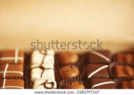 Sweet present concept. A set of hand-made chocolate candies in a box made of crafted paper. Close up. Text space. Indoor shot