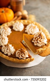 Sweet pumpkin pie decorated with whipped cream with a slice taken