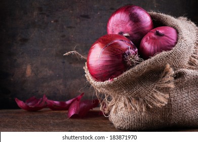 Sweet red onions in a canvas bag on a wooden surface - Powered by Shutterstock