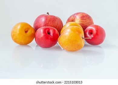 Sweet Ripe Juicy Plums And Red Apples On White Glass Surface