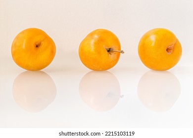 Sweet Ripe Juicy Yellow Plums On White Glass Surface