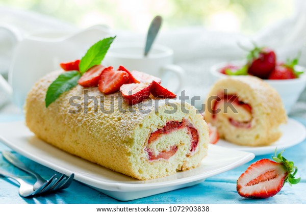 Sweet roll stuffed with\
strawberry and cream decorated with strawberries, powdered sugar\
and mint leaves