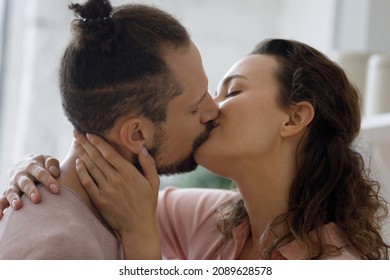 Sweet romantic couple in love kissing on lips at home, standing in kitchen, hugging, enjoying intimate sincere moment. Relationships, romance, affection, dating concept. Side view close up
