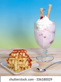 Sweet And Salty. French Fries Stacked Criss Crossed On A Square Plate Next To A Strawberry Sunday Ice Cream With Whipped Cream, Cherry And Pirouette Cookie On Top.