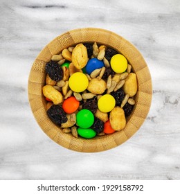 Sweet And Salty Trail Mix In A Wood Bowl On A Marble Tabletop Overhead View.