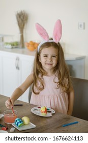 Sweet Smiley Little Girl Wearing Bunny Ears And Painting Easter Eggs.