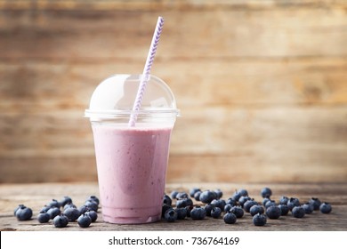 Sweet Smoothie In Plastic Cup With Blueberries On Wooden Table