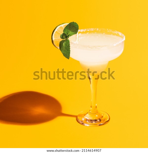 Sweet and sour.\
Margarita glass isolated on bright yellow neon background with\
shadow. Close-up. Complementary colors, white, blue and yellow.\
Copy space for ad. Pop\
art