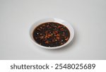 Sweet soy sauce chili sauce with sliced ​​red cayenne pepper served on a white plate placed on a white base and background (isolated white).