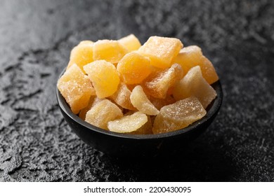 Sweet and spicy candied ginger in black bowl on dark stone background - Powered by Shutterstock