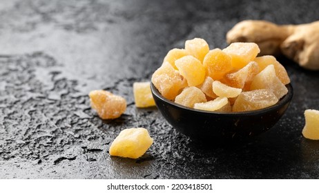 Sweet and spicy candied ginger in black bowl on dark stone background - Powered by Shutterstock