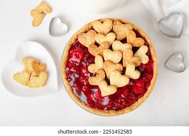 Sweet strawberry pie and heart-shaped plate of cookie hearts for Valentine's day on white background