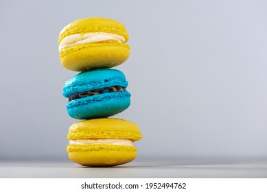 Sweet, tasty and colorful - blue and yellow french macarons on a light background, one on top of the other, a pyramid. The dessert is sweet. Selective focus. Sweet concept