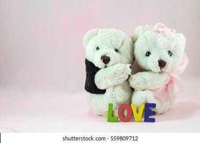 Sweet teddy bear couple in wedding dress with love letter on soft pink background.
