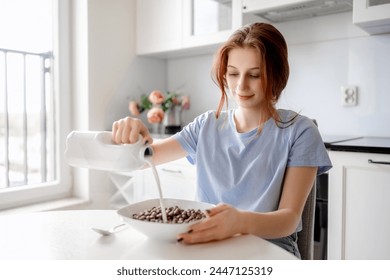 Sweet Teenage Girl Pours Milk Into Bowl With Dry Breakfast In Kitchen - Powered by Shutterstock