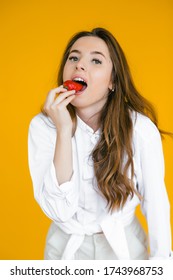 Sweet temptation. Beautiful young shirtless woman holding strawberry in her hand while standing against yellow background - Shutterstock ID 1743968753