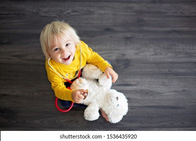 Sweet Toddler Child, Playing Doctor, Examining Teddy Bear Toy At Home, Isolated Background