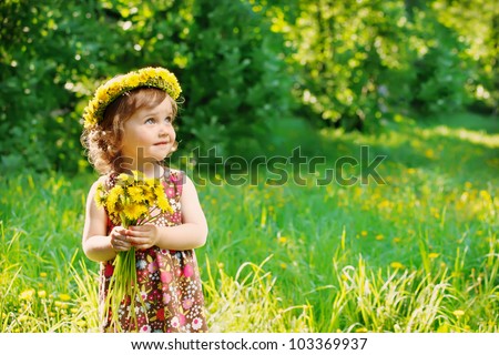 Sweet toddler girl with floral head wreath on and flowers bunch in hands