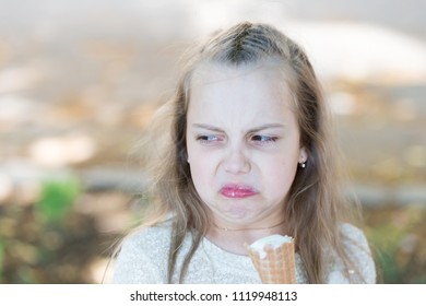 Sweet Tooth Girl Child With White Ice Cream In Waffle Cone. Kid Girl With Ice Cream Cone In Hand. Summer Treats Concept. Girl Sweet Tooth On Disgusted Face Eats Ice Cream, Light Background.