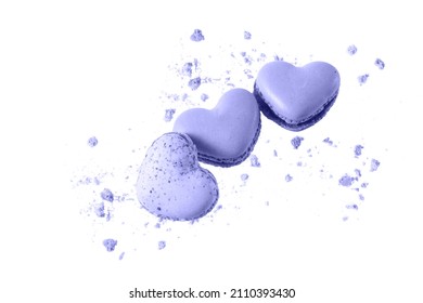 Sweet  violet macaroons macarons in heart  shape with crumbs  flying isolated on  white background. Pastry shop card in trendy color of 2022 Very Peri.