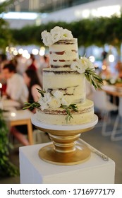 Sweet White Wedding Cake Decorated With White Flowers On A Gold Cake Stand At A Celebration