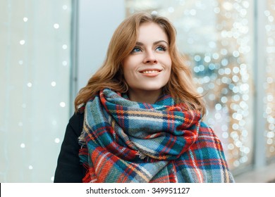Sweet woman with a smile in a beautiful stylish scarf on the background of lights