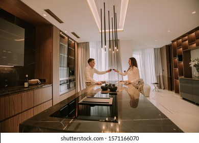 Sweet young couple having a romantic dinner and toasting with glasses of red wine at luxury kitchen - Powered by Shutterstock