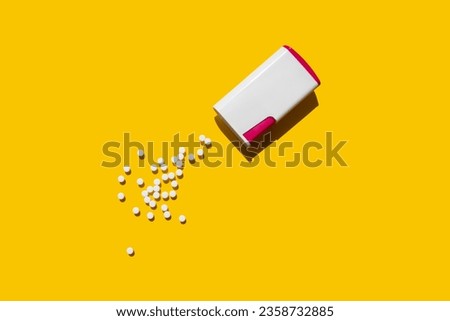sweetener packaging next to which lie sweet tablets on a yellow background