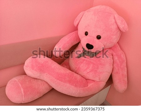 Sweetness personified: A big pink teddy bear takes a relaxed seat on a matching pink chair, exuding sheer cuteness in every plush detail.