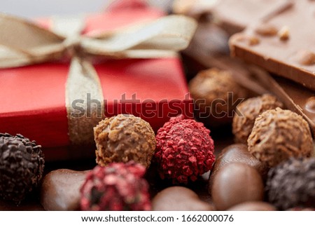 sweets concept - close up of handmade chocolate candies and red gift box