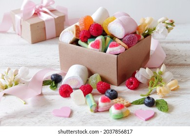 Sweets in a gift box. Jelly candies, sugar candies, marshmallows, flowers, raspberries and blueberries