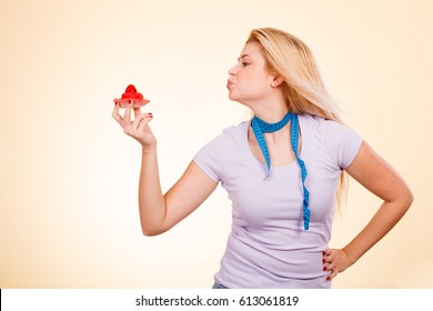Sweets, junk food, sugar temptation on diet concept. Woman with measuring tape around her neck holding sweet delicious strawberry cupcake sending air kisses to dessert.