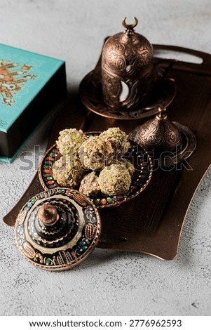 Sweets made from nuts and sugar are placed on a decorative tray. A pair of coffee cups sit beside the sweets. A box is also visible in the background.