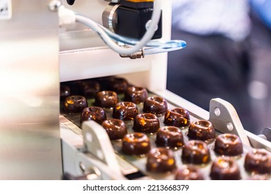 sweets production and industry concept - chocolate candies processing on conveyor at confectionery shop. High quality photo