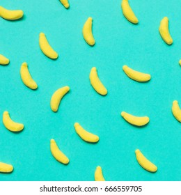 sweets in the shape of bananas on a blue background. minimal flat lay. party food