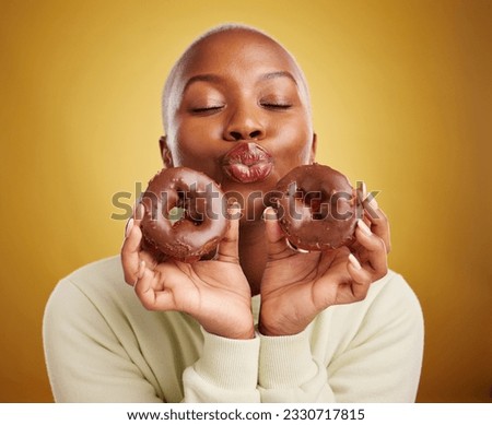 Sweets, smile and black woman with donuts, funny and happiness with expression, crazy or silly. Female person, dessert or goofy model with facial, chocolate or sugar against a brown studio background