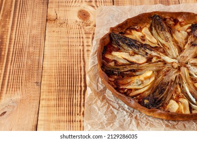 sweety salty tart with the ingredients of chicory and pears, wooden background, copy space