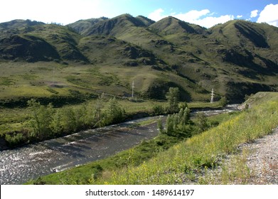 A Swift River Flowing At The Foot Of The Mountains Through A Fertile Valley. Altai, Siberia, Russia.