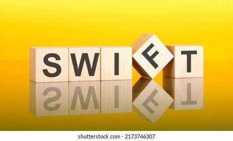 Swift Word Written On Wood Block. Yellow Background. Business Concept. Swift - Society For Worldwide Interbank Financial Telecommunications