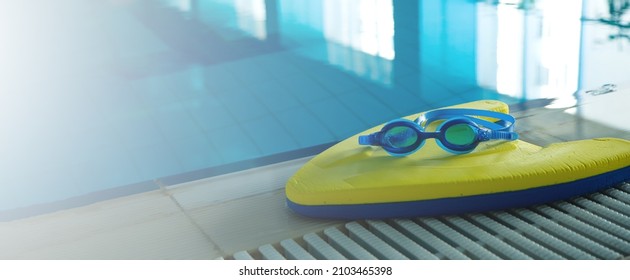 Swim board with Goggles on beside of the swimming pool in sports center. swimming training concept. banner copy space for text - Powered by Shutterstock