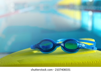 Swim Board With Goggles On Beside Of The Swimming Pool In Sports Center. Swimming Training Concept. Copy Space For Text